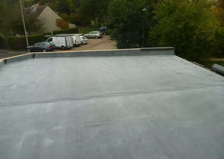 toiture plate couverte en membrane EPDM, l'arrière plan montre une zone résidentielle.