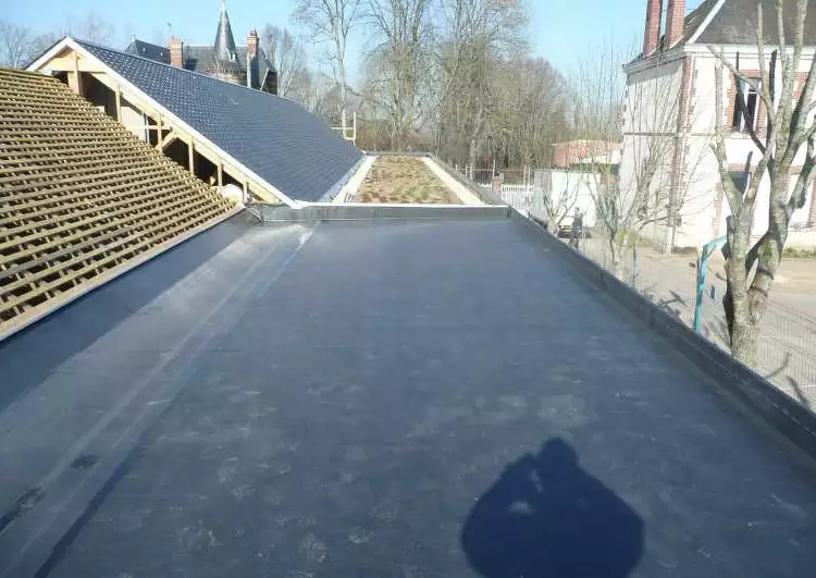 bande de toiture plate en partie inférieure d'une partie inclinée, au premier plan la membrane EPDM est posée sur la partie plate, au fond la végétalisation est posée sur la membrane EPDM.